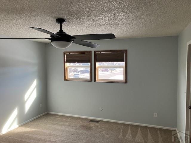 spare room featuring a textured ceiling, carpet flooring, visible vents, and baseboards