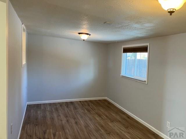 spare room with dark wood-style floors, baseboards, and a textured ceiling