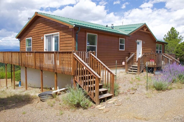 back of house featuring metal roof, stairway, and a wooden deck