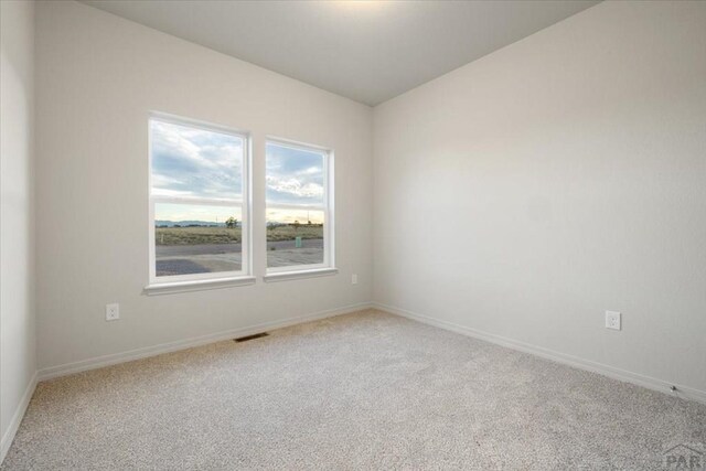 empty room featuring carpet, visible vents, and baseboards