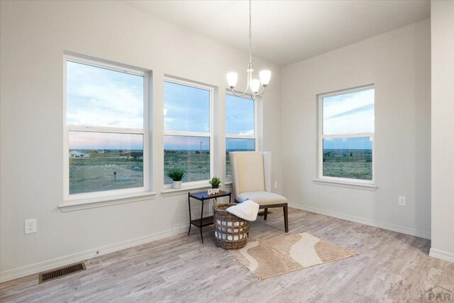 sitting room featuring light wood-type flooring, baseboards, visible vents, and a chandelier