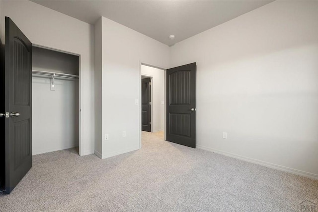 unfurnished bedroom featuring light carpet, a closet, and baseboards