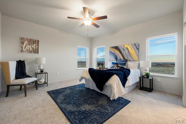 carpeted bedroom featuring multiple windows, a ceiling fan, and baseboards