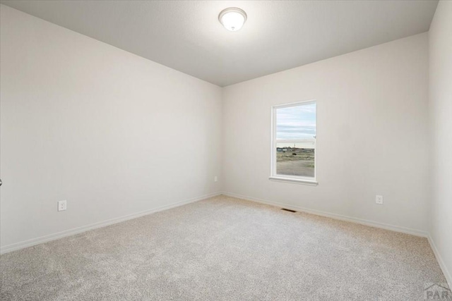 spare room with carpet, visible vents, and baseboards