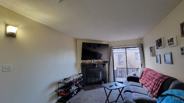 living area featuring a glass covered fireplace, carpet flooring, and a textured ceiling