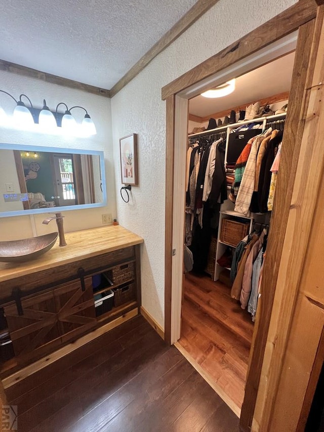 10421 Linger Longer Ln, Rye, CO 81069 - bathroom with a textured wall, a textured ceiling, hardwood / wood-style flooring, a spacious closet, and vanity