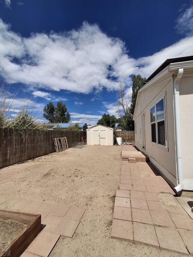 view of yard with an outbuilding, a patio, a storage unit, and a fenced backyard