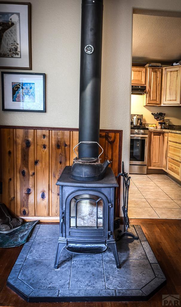 8946 Central Ave, Beulah, CO 81023 - detailed view of gas range, a wood stove, under cabinet range hood, and a textured ceiling