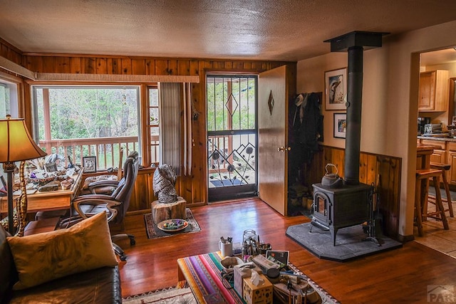 8946 Central Ave, Beulah, CO 81023 - living room featuring a wood stove, wooden walls, wood finished floors, and a textured ceiling