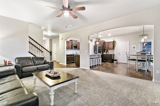 6740 Spruce Hill Ct, Colorado Springs, CO 80923 - living area featuring dark colored carpet, ceiling fan, arched walkways, and stairs