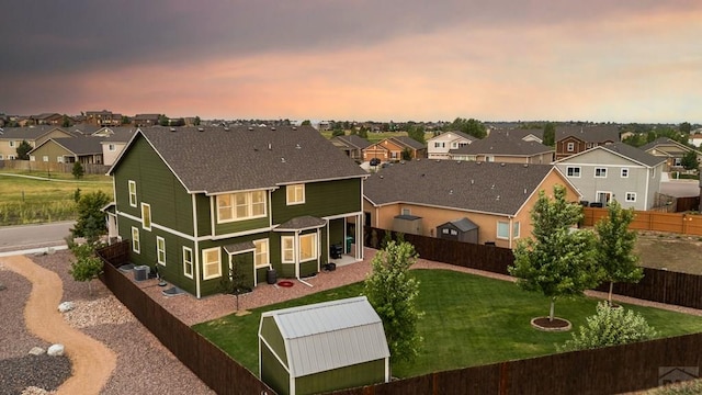 6740 Spruce Hill Ct, Colorado Springs, CO 80923 - back of house at dusk featuring a residential view, a fenced backyard, and an outbuilding