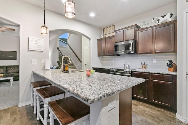 6740 Spruce Hill Ct, Colorado Springs, CO 80923 - kitchen featuring arched walkways, dark brown cabinetry, stainless steel appliances, wood finished floors, and recessed lighting