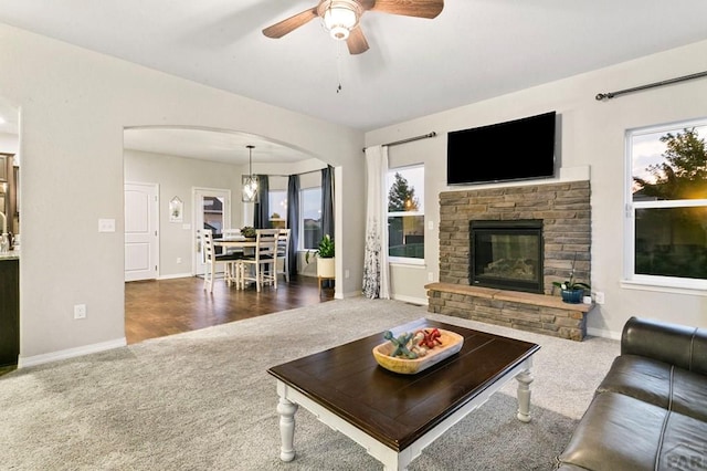 6740 Spruce Hill Ct, Colorado Springs, CO 80923 - living room featuring carpet, arched walkways, ceiling fan, and a stone fireplace