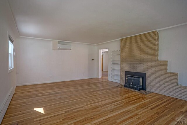 unfurnished living room featuring light wood-style flooring, ornamental molding, baseboard heating, a brick fireplace, and a wall mounted AC