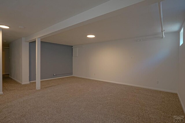 finished basement featuring light colored carpet and baseboards