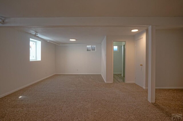 below grade area with light colored carpet and baseboards