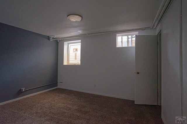 basement with dark carpet and baseboards