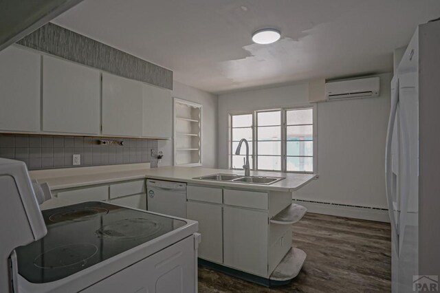 kitchen featuring a baseboard heating unit, an AC wall unit, white cabinets, a sink, and white appliances