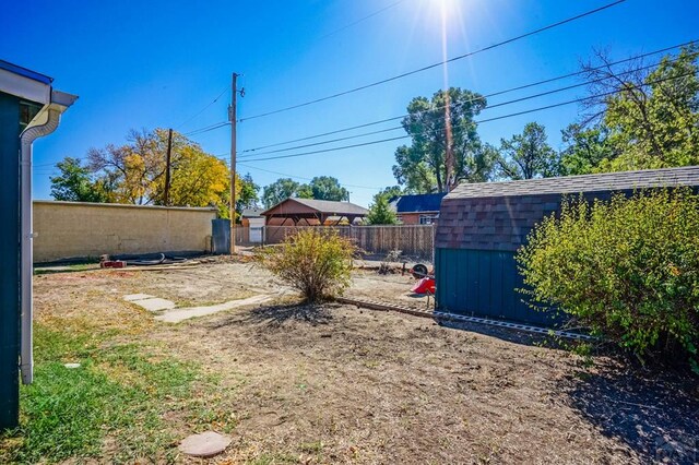 view of yard featuring a storage unit, an outdoor structure, and a fenced backyard