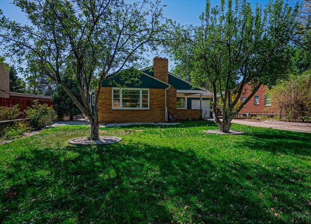 view of front of property with a chimney, fence, and a front yard