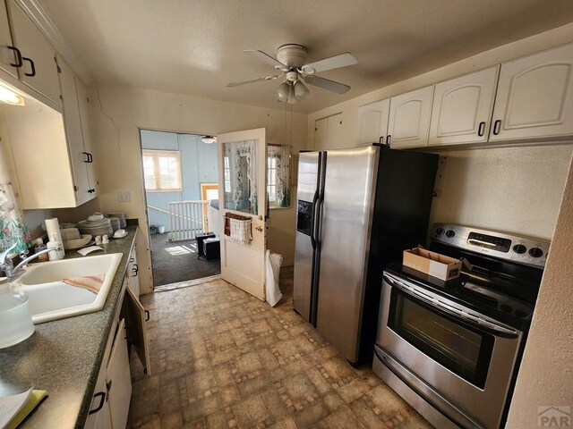 kitchen featuring ceiling fan, stainless steel appliances, a sink, white cabinets, and light countertops