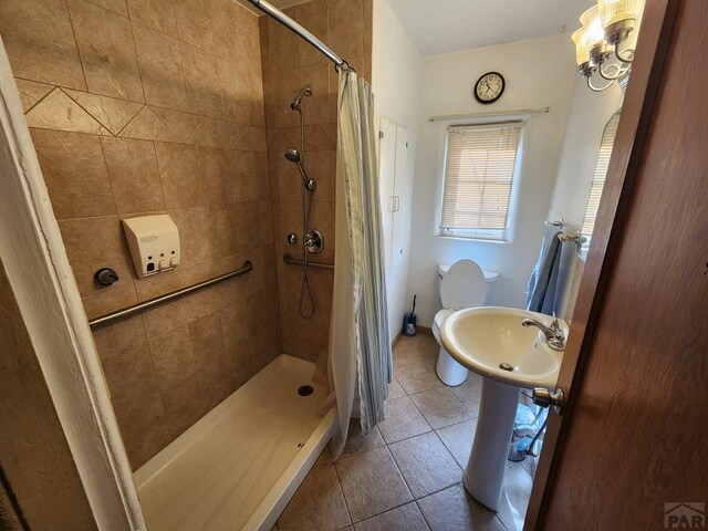 full bath featuring toilet, a stall shower, a sink, and tile patterned floors