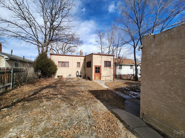 view of front of property with fence, an outdoor structure, and stucco siding