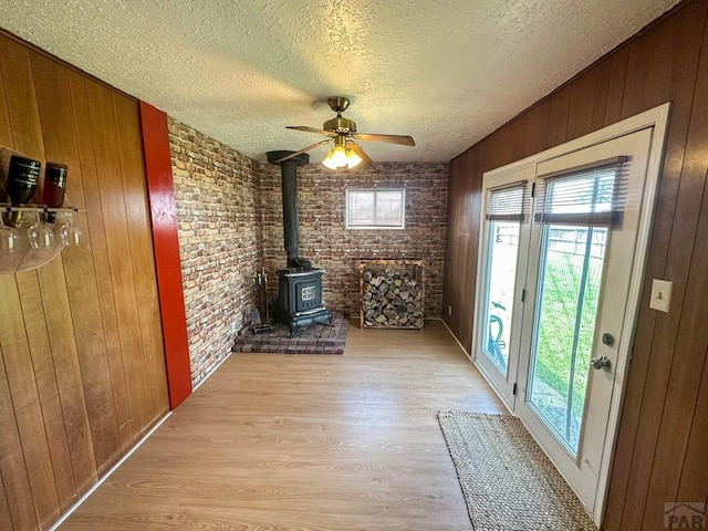 620 S 7th St, Springfield, CO 81073 - doorway with a wood stove, light wood-style floors, a textured ceiling, wooden walls, and brick wall