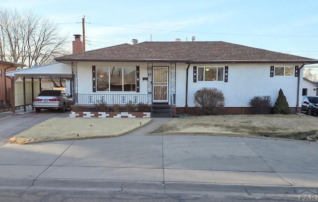 single story home featuring a chimney, stucco siding, a porch, an attached carport, and driveway