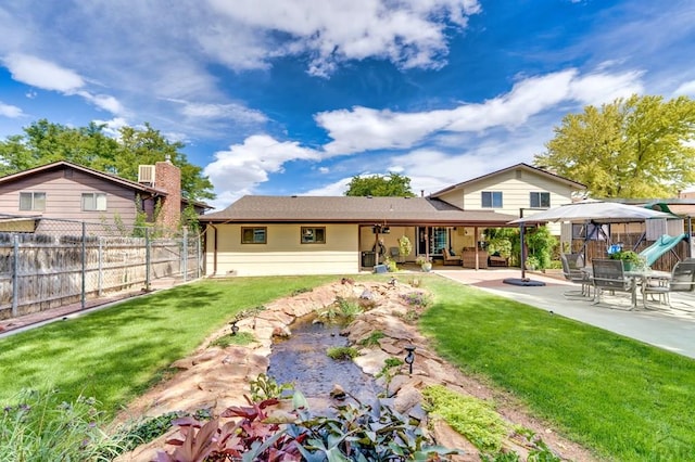 rear view of property featuring a lawn, a patio area, and fence