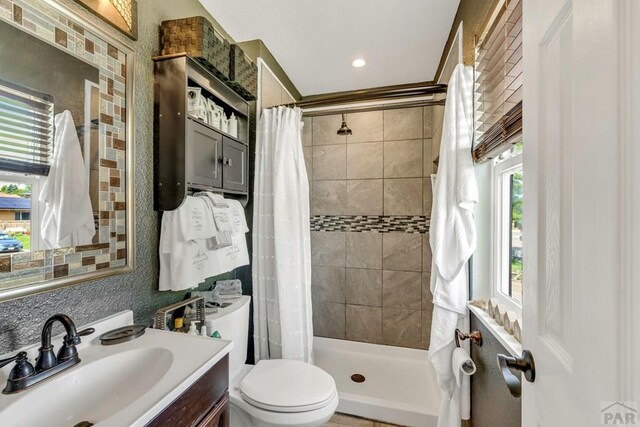 bathroom with a stall shower, vanity, and toilet