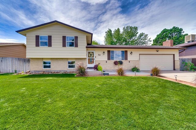 split level home featuring a garage, a front yard, concrete driveway, and fence