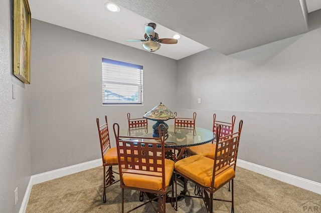 carpeted dining room featuring ceiling fan and baseboards