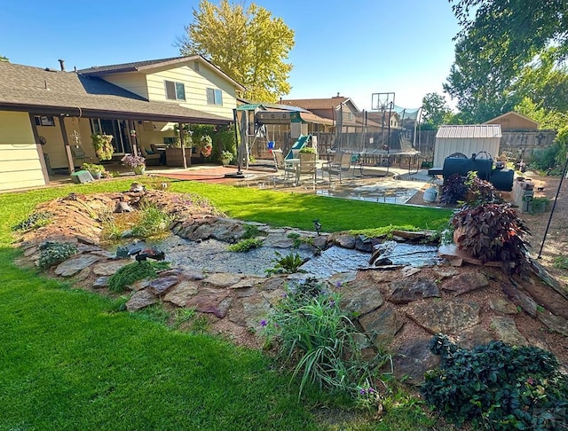 view of yard featuring an outbuilding, a trampoline, fence, a patio area, and a shed