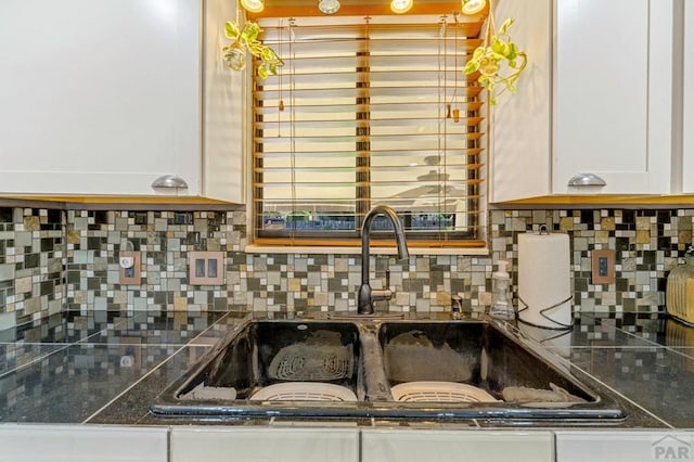 kitchen featuring backsplash, white cabinets, and a sink