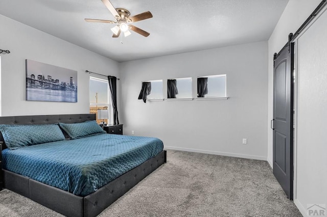 1437 Chuckwagon Ln, Pueblo West, CO 81007 - carpeted bedroom featuring a barn door, baseboards, and a ceiling fan