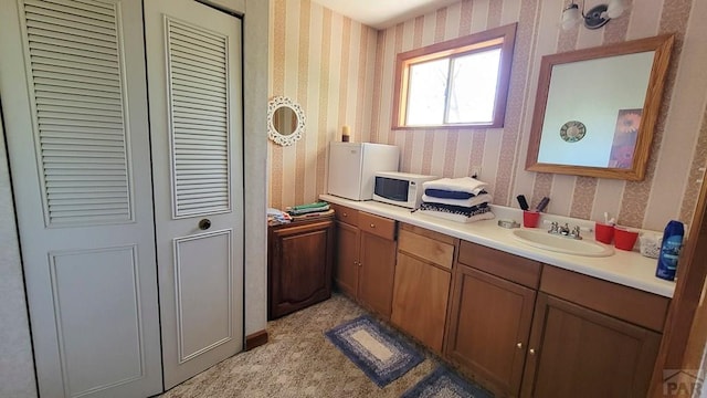 bathroom with wallpapered walls, a closet, and vanity