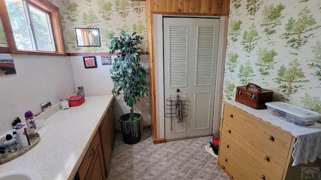 bathroom with wallpapered walls and a closet