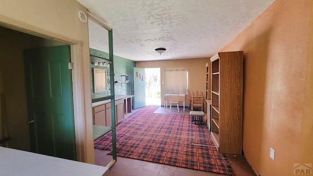hall with a textured ceiling and carpet flooring