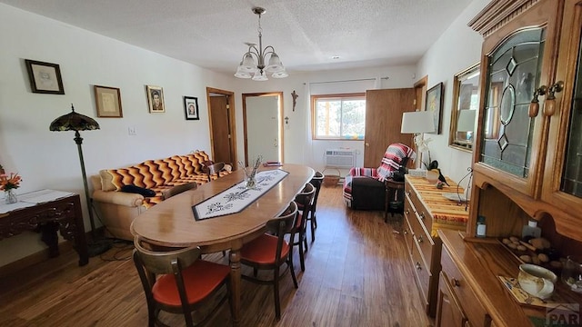 dining area with dark wood-style flooring, a chandelier, a wall mounted air conditioner, and a textured ceiling