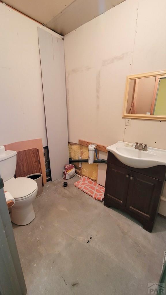 bathroom featuring unfinished concrete floors, toilet, and vanity
