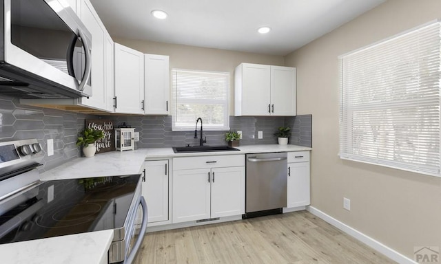 3009 Baystate Ave, Pueblo, CO 81005 - kitchen with stainless steel appliances, a sink, light wood-style flooring, backsplash, and recessed lighting