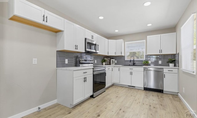 3009 Baystate Ave, Pueblo, CO 81005 - kitchen featuring stainless steel appliances, a sink, light wood-style floors, decorative backsplash, and baseboards