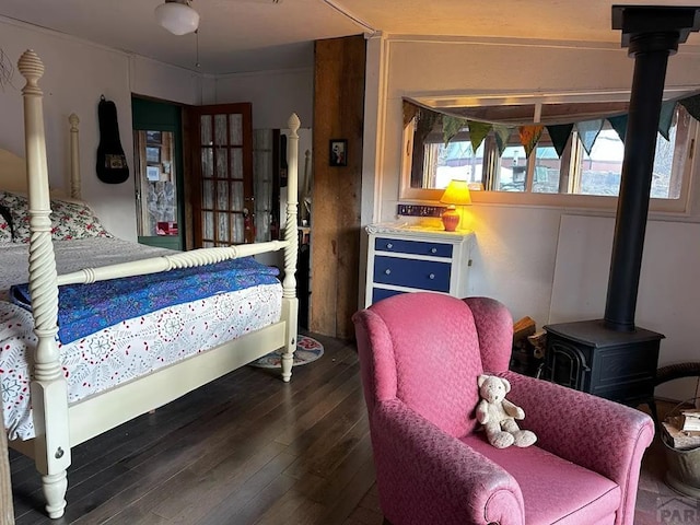 bedroom featuring a wood stove and dark wood finished floors