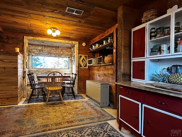 dining room with wood ceiling, visible vents, and wooden walls