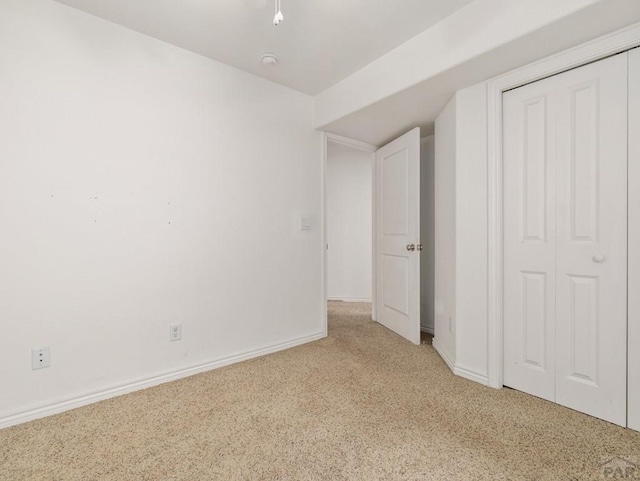 unfurnished bedroom featuring a closet, carpet floors, and baseboards