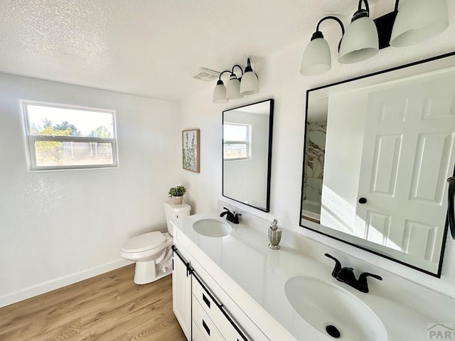 full bath with a sink, a textured ceiling, baseboards, and wood finished floors