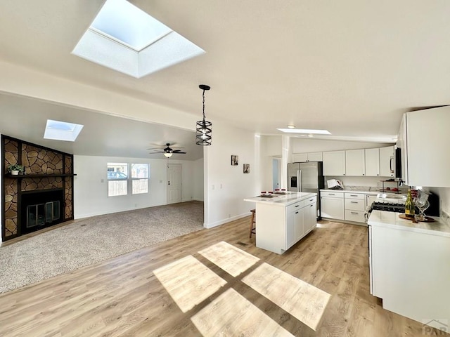 kitchen with light countertops, hanging light fixtures, open floor plan, white cabinets, and a kitchen island