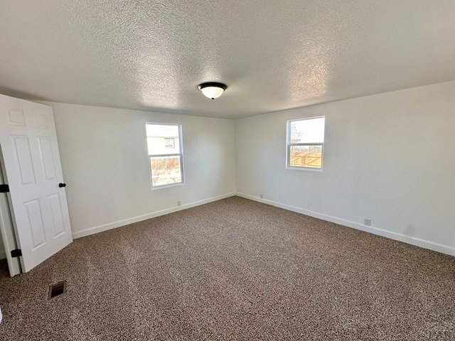 unfurnished room with carpet floors, a healthy amount of sunlight, visible vents, and baseboards