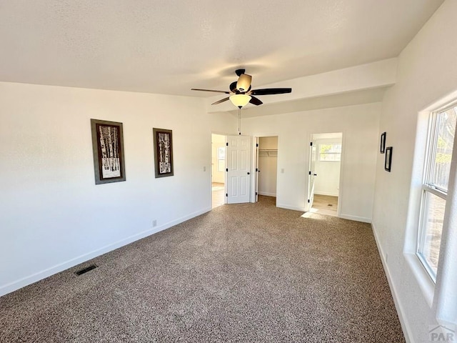 unfurnished bedroom with carpet floors, baseboards, multiple windows, and visible vents